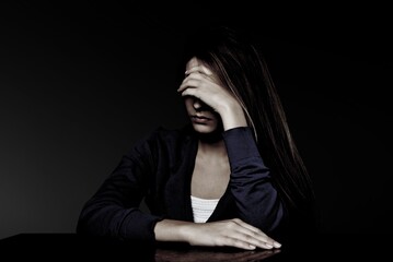 Abused sad woman hide herself in dark background