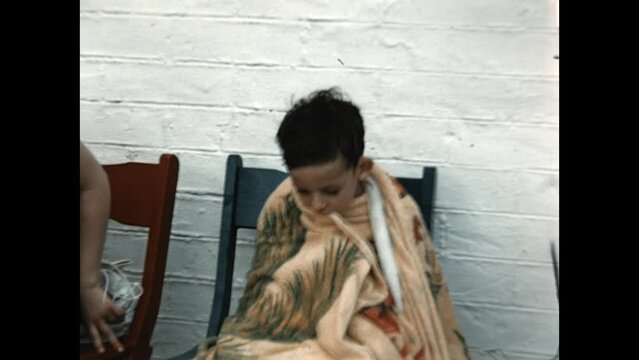 Warming Up After a Swim 1955 - A boy is wrapped in a towel to warm himself as his mother sits nearby in 1955. 