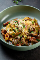 Pasta Bolognese with spices, Italian pasta dish with minced meat and tomatoes in a dark plate on a stone background