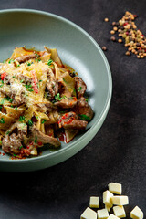 Pasta Bolognese with spices, Italian pasta dish with minced meat and tomatoes in a dark plate on a stone background