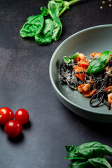 black paste with cuttlefish ink basil ad tomato on blavk background