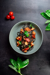 black paste with cuttlefish ink basil ad tomato on blavk background