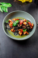 black paste with cuttlefish ink basil ad tomato on blavk background