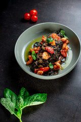 black paste with cuttlefish ink basil ad tomato on blavk background