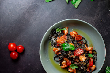 Fototapeta na wymiar black paste with cuttlefish ink basil ad tomato on blavk background