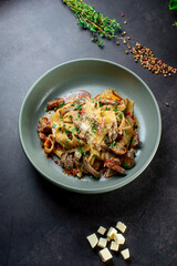 Pasta Bolognese with spices, Italian pasta dish with minced meat and tomatoes in a dark plate on a stone background