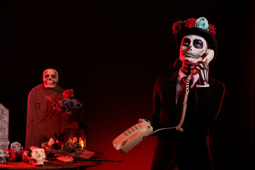 Beautiful model answering landline phone call before celebrating dios de los muertos traditional...