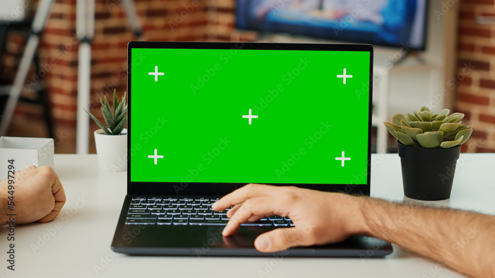 Poster young adult working on laptop with green screen template at desk, checking blank chroma key and isol