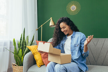 Young beautiful curly haired hispanic woman received package from online store, happy and satisfied...