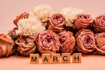 Orange roses are laid out on a monochromatic background. Spring march
