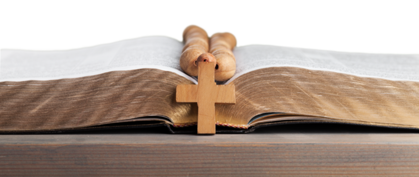 Rosary beads on open bible on wooden table