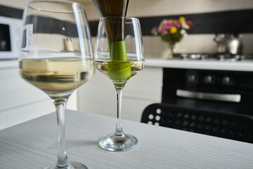 Two glasses of white wine on the kitchen table. Celebrate and enjoy the moment. Tasting of alcoholic beverages. Glass of wine close-up