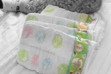 happy baby holding diaper in hands. Close up. baby is surrounded by diapers on a white background