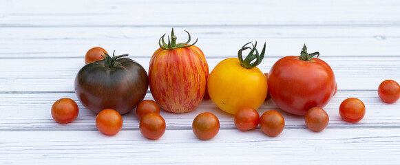 Variety of colorful tomatoes on the white wooden rustic table.