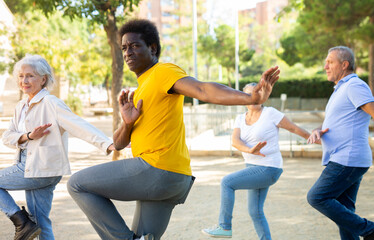 Carefree diverse people spending time together dancing rhythmic dance aerobic workout on a sandy...