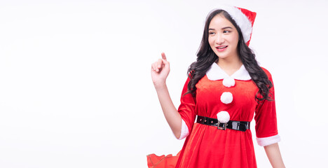 Cheerful surprise asian woman wear Santa Claus dress with Christmas hat use finger pointing present copy space standing on white background. Excited young girl Santa Claus dress merry Christmas winter