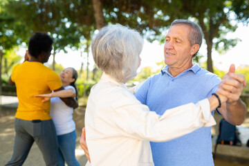 Happy multiracial adult people with different ages dancing in pairs outdoors having a good time together
