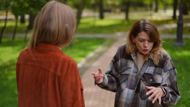 Angry unsatisfied irritated woman gesturing in slow motion arguing with friend in park. Portrait of dissatisfied annoyed Caucasian lady quarreling outdoors