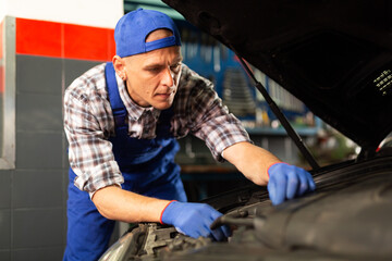 Fototapeta na wymiar Mechanic technician working at service station, repairing car