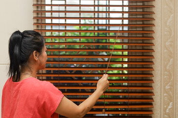 woman opening wooden blinds