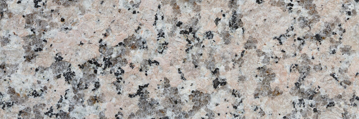 Granite texture. Natural gray granite with a grainy pattern. Stone background. Solid rough surface of rock. Durable construction and decoration material. Close-up.