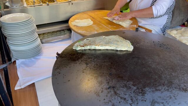 Anonymous woman preparing traditional Turkish borek and puts on big hot pan. Restaurant chef cooking stuffed dough bread in Istanbul, Turkey