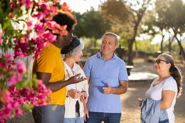 Portrait of multiracial mature adult people standing outside at park on a sunny day and carelessly...