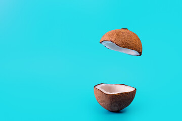 Coconut split in half and flying on isolated turquoise background. Coconut levitating. podium...