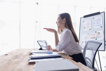 Young business multiethnic women or cheerful Asian lady working onlaptop and call phone at workplace office, financial documents having phone conversation, copy space
