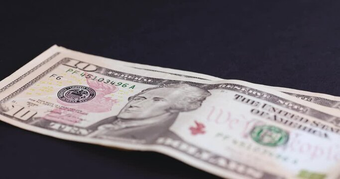 counting American ten-dollar bills on black paper, American currency dollars in cash