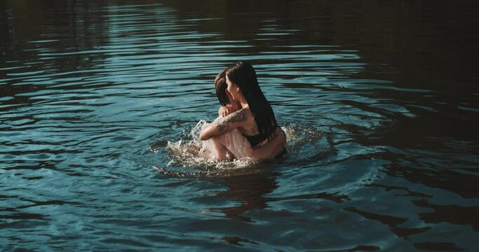 Young couple hugging each other in the lake at sunset