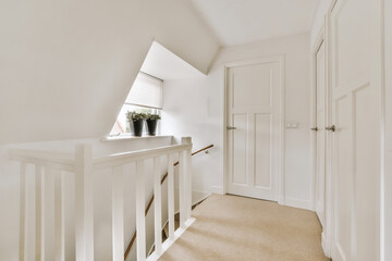 Closed white door of room located near framed pictures and stylish lamp on top of stairway at home