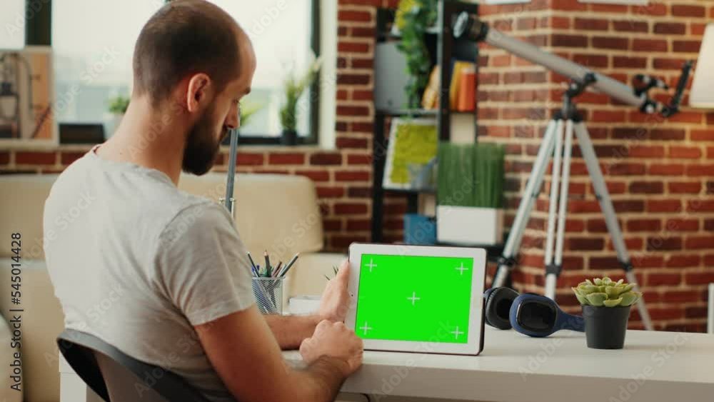 Poster freelancer working with isolated horizontal greenscreen display on wireless gadget, using chroma key