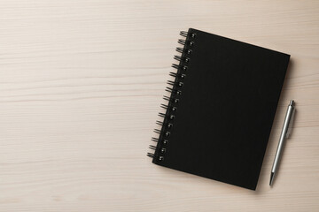 Notebook and pen on white wooden table, flat lay . Space for text