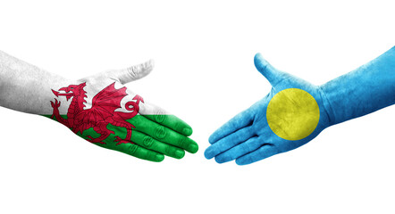 Handshake between Palau and Wales flags painted on hands, isolated transparent image.