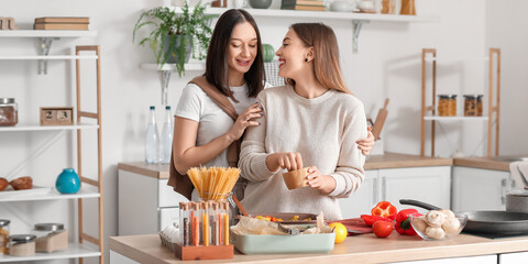 Young lesbian couple cooking dinner in kitchen