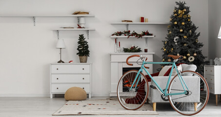 Interior of light living room with bicycle, sofa and Christmas trees