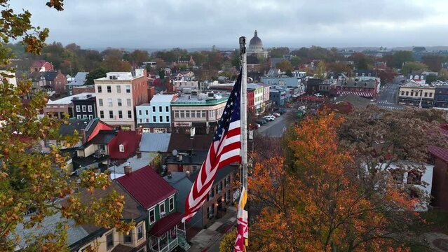 Patriotic Annapolis Maryland on rainy autumn morning. Aerial of USA and MD flags framed by colorful trees in fall.