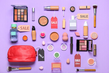 Red bag with cosmetics, accessories and sale tags on lilac background