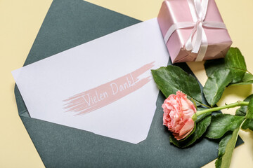 Card with text VIELEN DANK, envelope, rose and gift box on beige background