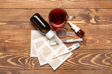 Mustard plasters with medicines, cup of tea and thermometer on wooden background