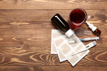 Mustard plasters with medicines, cup of tea and thermometer on wooden background