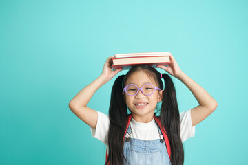 Portrait of happy lazy little girl covering head with book and smiling to camera.