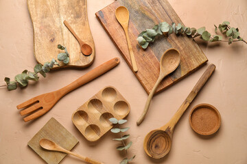 Fototapeta na wymiar Wooden cooking utensils and eucalyptus branches on beige background