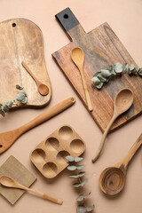 Wooden cooking utensils and eucalyptus branches on beige background