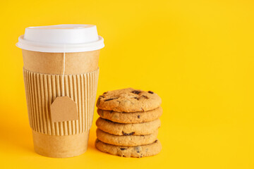 Paper cup of tea and tasty cookies on color background