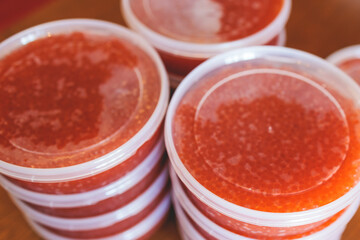 Red caviar plactic jars, rows of salted canned red caviar containers filled to the top on a seafood...