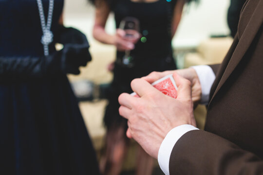 Magician illusionist with a deck of cards showing card tricks focus in front of wealthy rich guests on party event wedding celebration, juggler show, prestidigitator performance on a stage