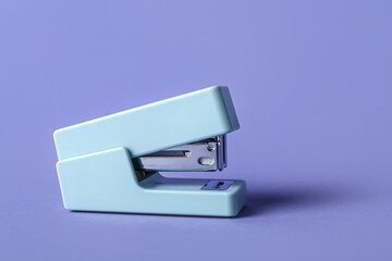 Office stapler on lilac background
