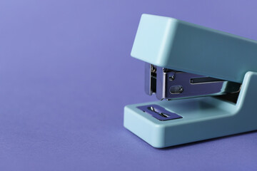 Office stapler on lilac background, closeup